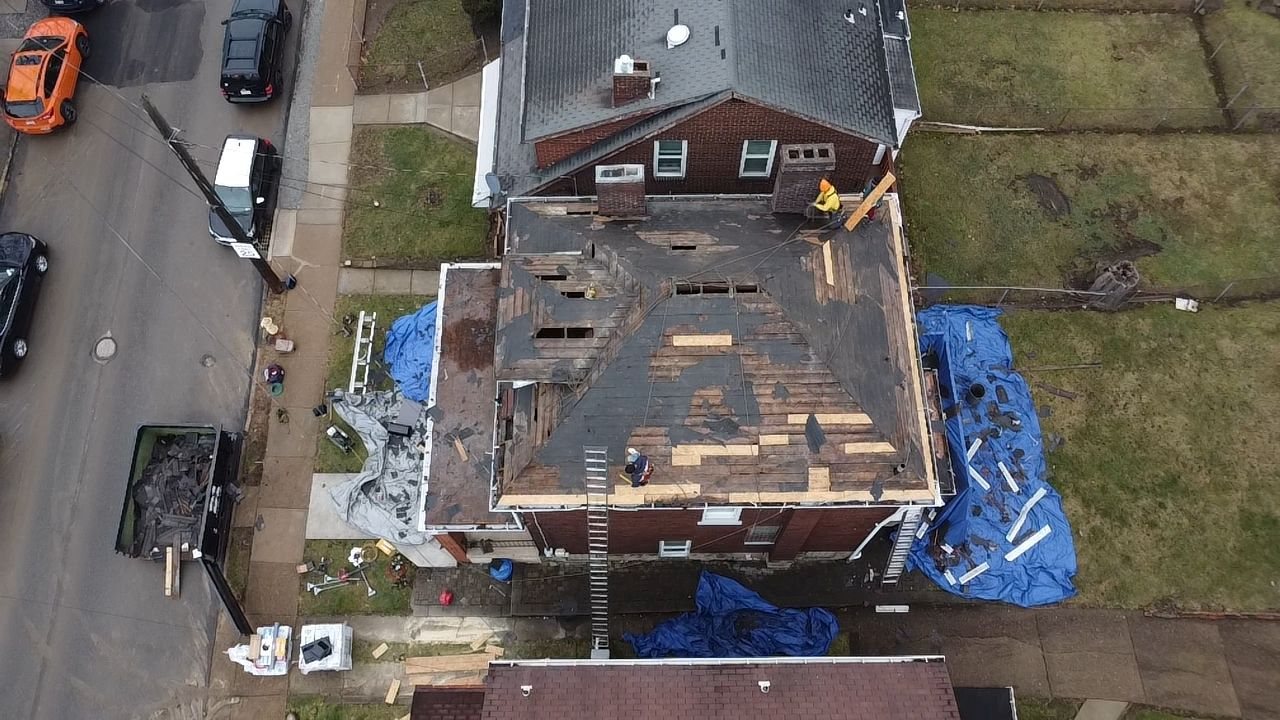 Drone view of a roof tear off with blue tarps on the ground in Pittsburgh, Alan Construction