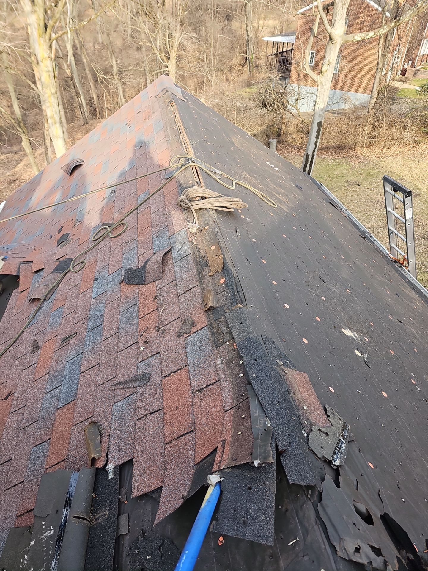 Old red shingles being stripped from a roof ridge in Pittsburgh, Alan Construction