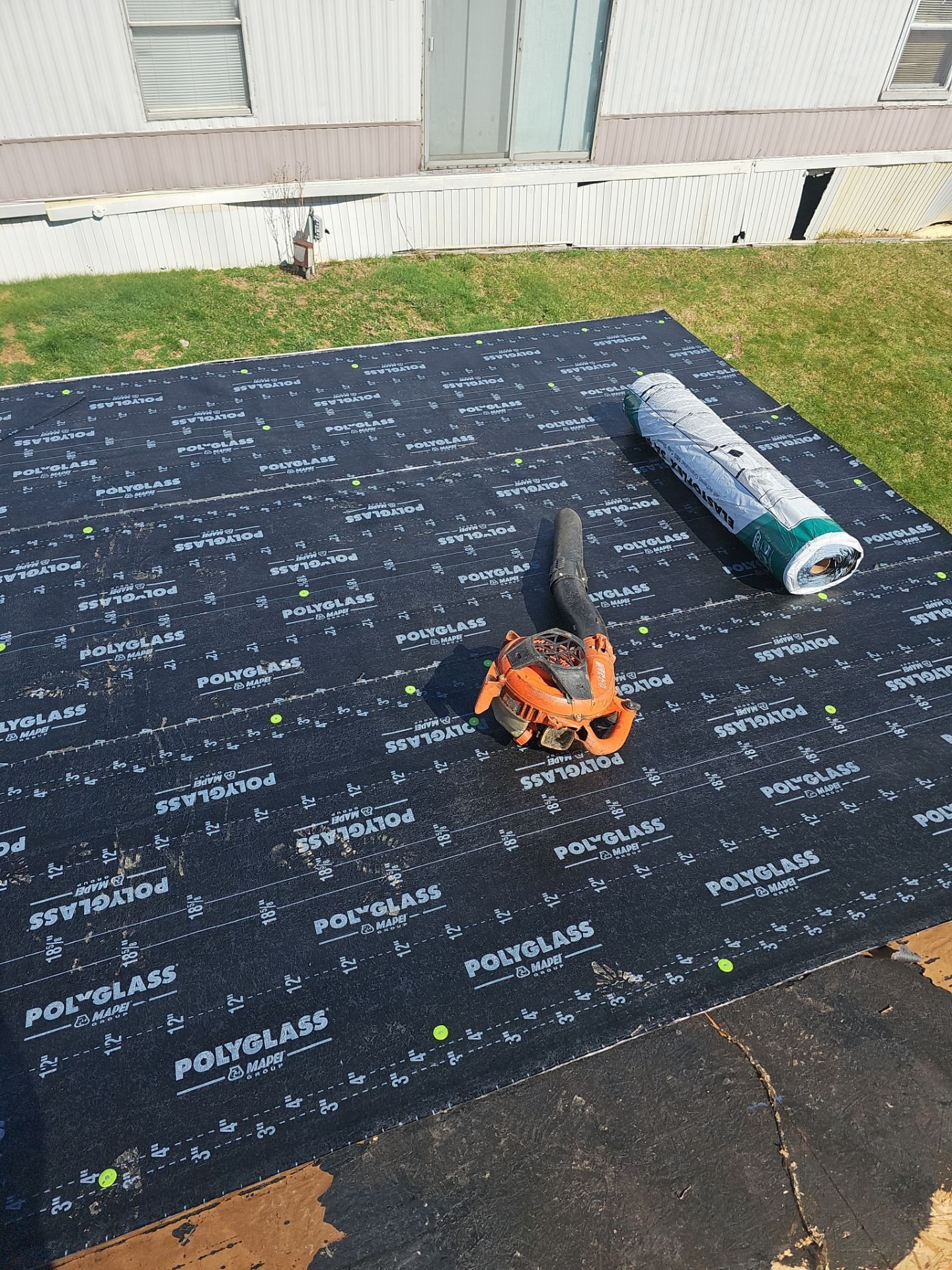 Black self adhered underlayment on a low slope roof with a roller tool in Oakdale, Alan Construction