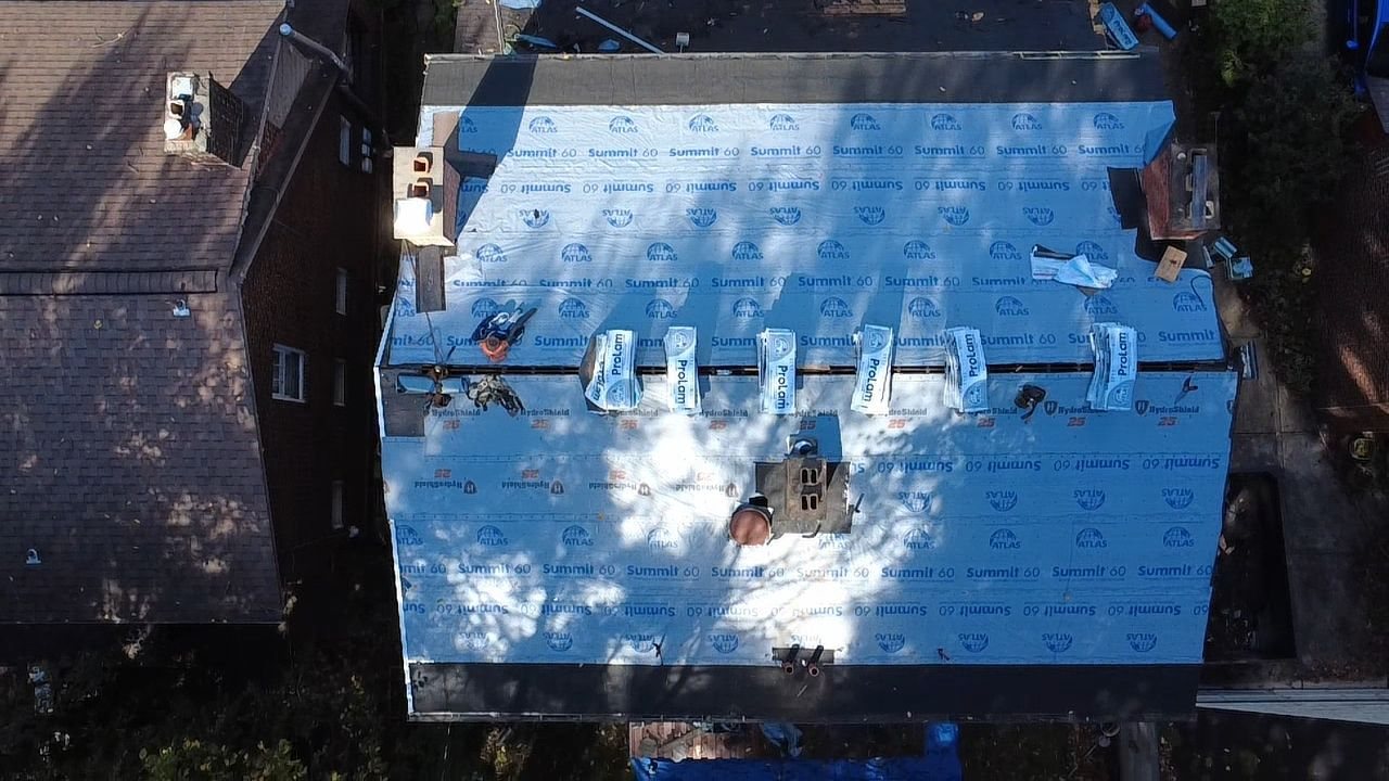 Drone view of a roof fully covered in synthetic underlayment with shingle bundles in Pittsburgh, Alan Construction