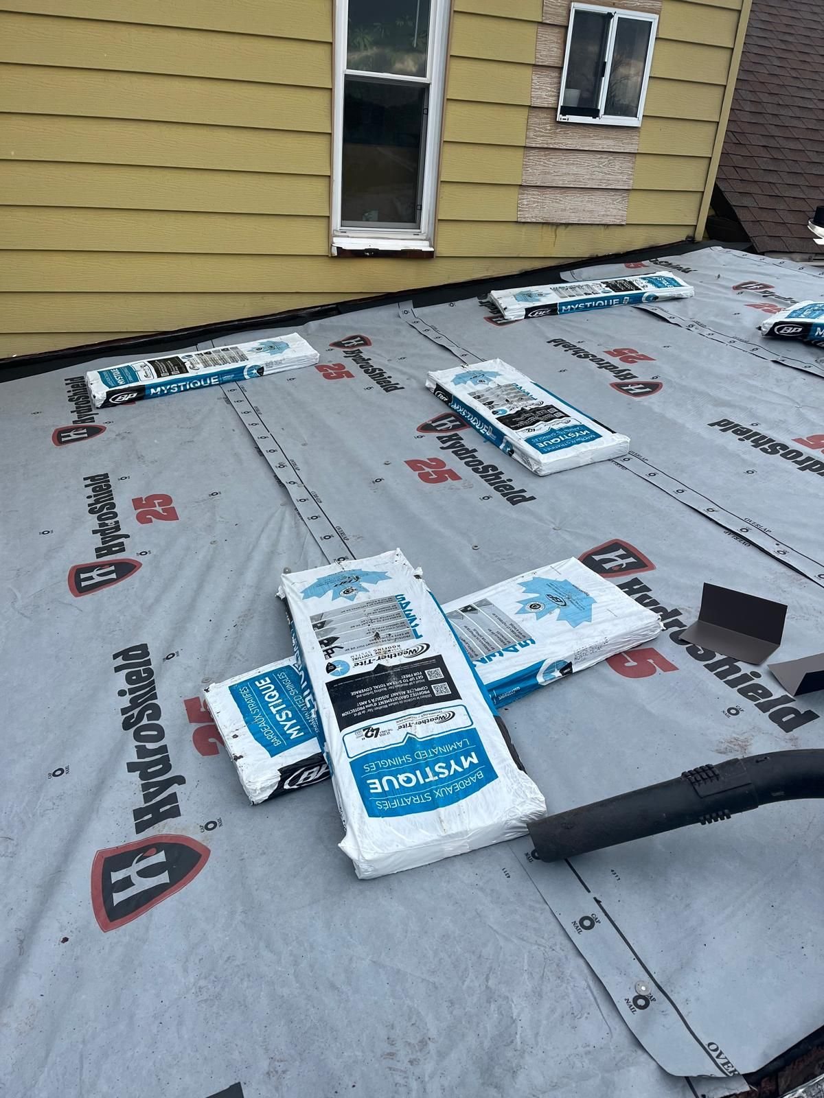 Synthetic underlayment covering a roof deck with shingle bundles staged on top in Pittsburgh, Alan Construction