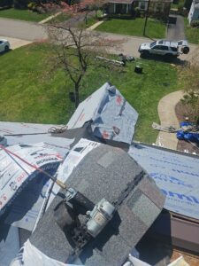 Synthetic underlayment covering hip roof sections above a green yard in Pittsburgh, Alan Construction