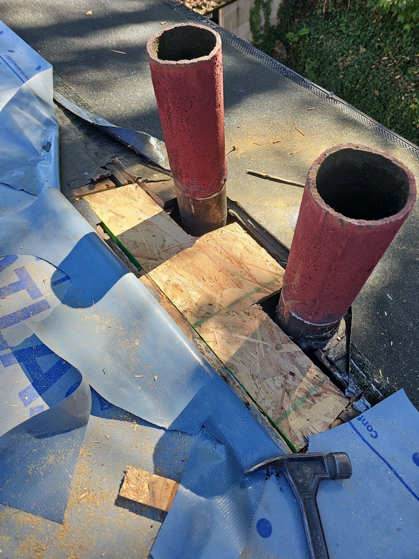 Two red flue pipes rising through new decking and underlayment in Pittsburgh, Alan Construction