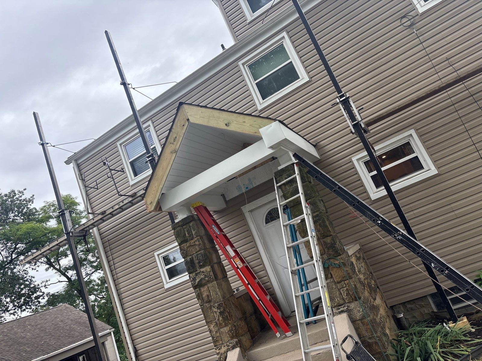 Ladders and pump jacks against a home during siding work in Carnegie, Alan Construction