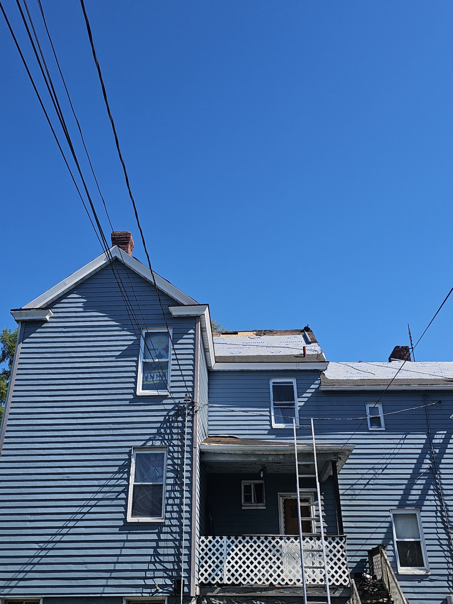 Blue sided house rear with a ladder against the upper porch in Glassport, Alan Construction