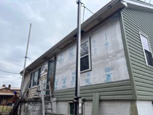 Wall half covered in house wrap and half in green siding in Monongahela, Alan Construction