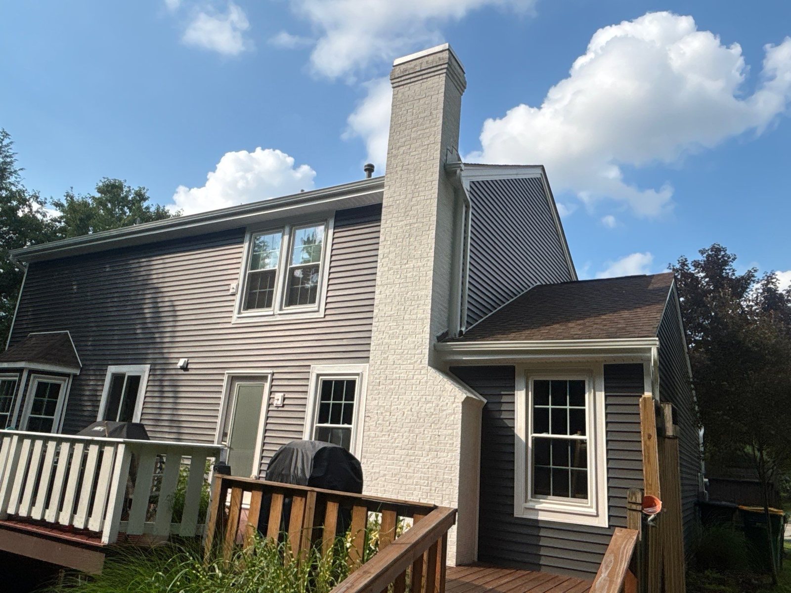 Rear of a home with gray vinyl siding and a white chimney in Pittsburgh, Alan Construction