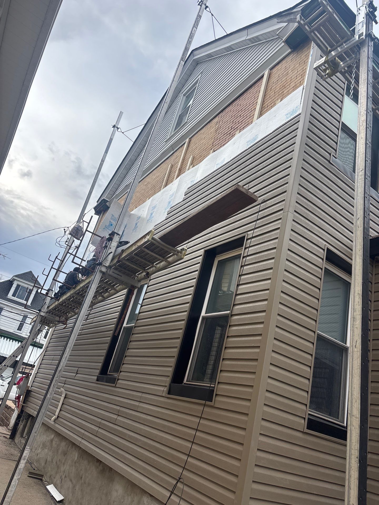 Tall wall with new tan siding and a ladder in Pittsburgh, Alan Construction