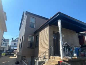 House with new tan siding and black porch roof trim in Pittsburgh, Alan Construction
