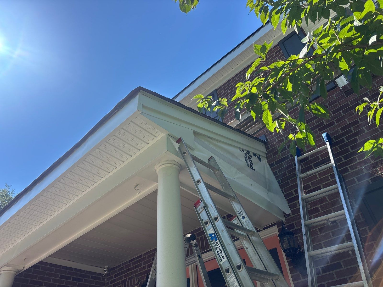 White soffit and porch ceiling with ladders against a brick wall in Pittsburgh, Alan Construction
