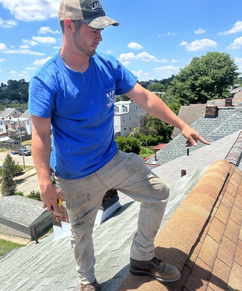 Roofing contractor inspecting shingles on residential rooftop in Pittsburgh, demonstrating quality craftsmanship and expertise.