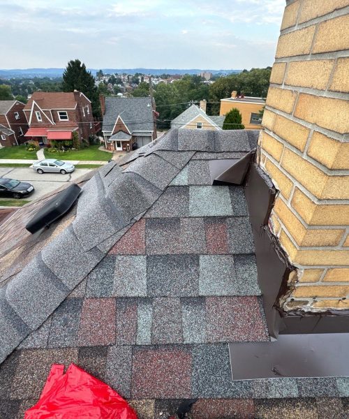Brown metal flashing along a yellow brick chimney on multicolor shingles in Munhall, Alan Construction