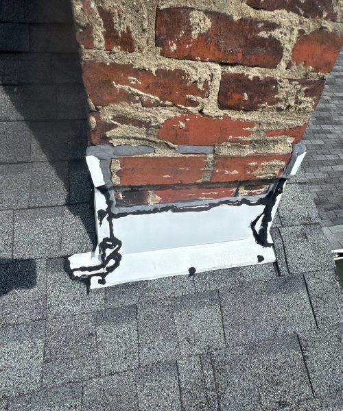 New white aluminum flashing wrapped around the base of a red brick chimney in Pittsburgh, Alan Construction
