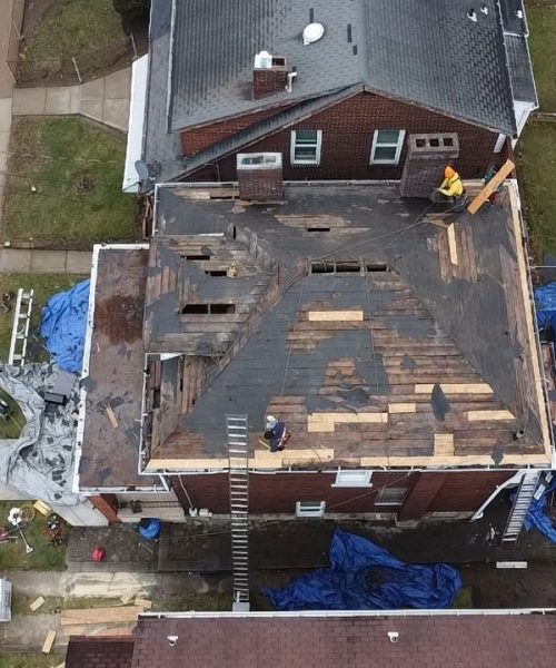 Drone view of a roof tear off with blue tarps on the ground in Pittsburgh, Alan Construction