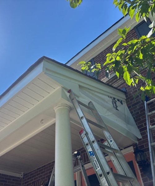 White soffit and porch ceiling with ladders against a brick wall in Pittsburgh, Alan Construction