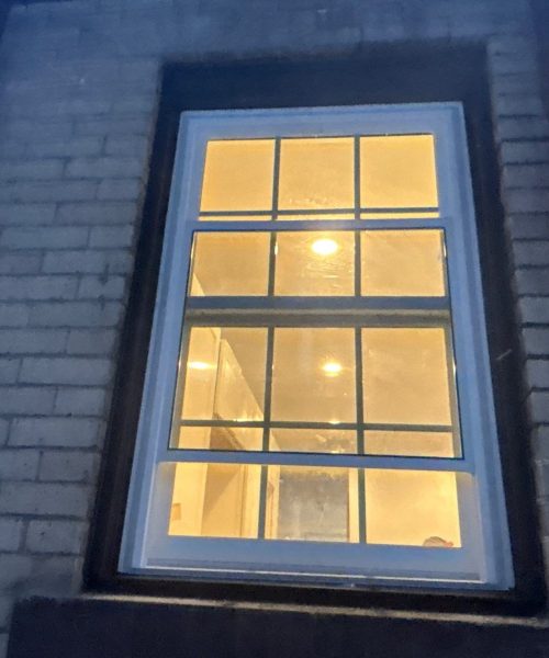 Lit double hung window in a brick wall at dusk in Pittsburgh, Alan Construction