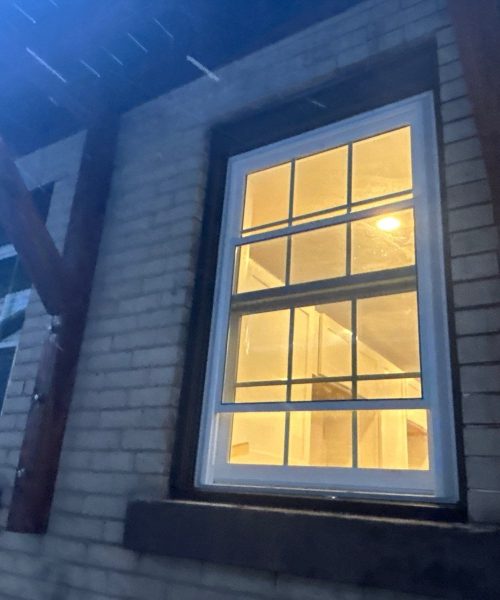 New windows glowing inside a brick facade at night in Pittsburgh, Alan Construction