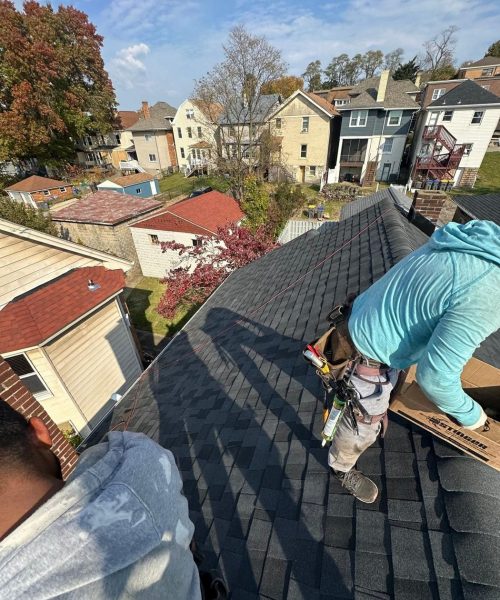 Alan Construction roofer installing shingles above Dormont rooftops