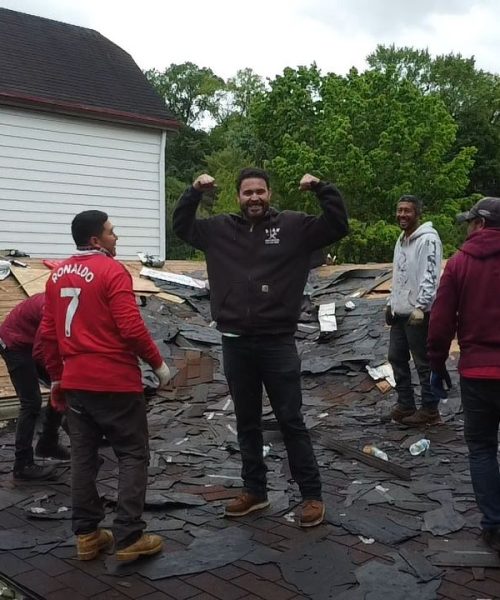 Group of workers celebrating on a roof during a construction project, showcasing teamwork and roofing expertise.